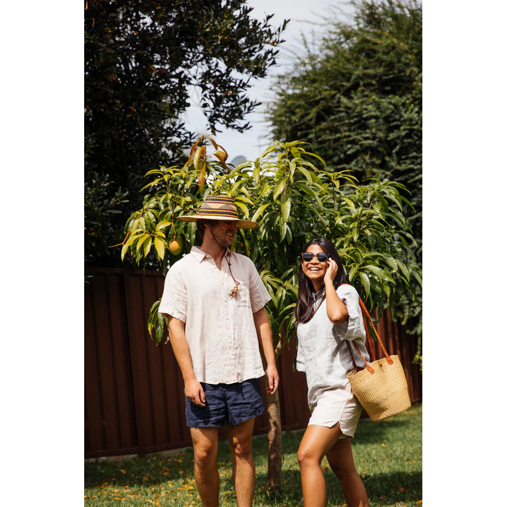 French flax linen unisex boxer shorts, loose, comfy and playful for men and women of all shapes and sizes - Available in 5 colours: White, Pinstripe, Natural, Navy & Charcoal – Navy boxer shorts pictured on a man standing next to a woman wearing the white linen shorts - available at LOVINLIFE Co Byron Bay for all your gifts, candles and interior decorating needs