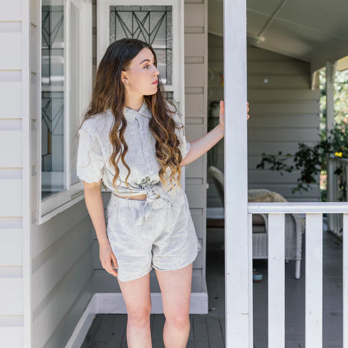 French flax linen unisex boxer shorts, loose, comfy and playful for men and women of all shapes and sizes - Available in 5 colours: White, Pinstripe, Natural, Navy & Charcoal – Pinstripe boxer shorts pictured on woman on the veranda of an old house - available at LOVINLIFE Co Byron Bay for all your gifts, candles and interior decorating needs