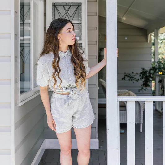 French flax linen unisex boxer shorts, loose, comfy and playful for men and women of all shapes and sizes - Available in 5 colours: White, Pinstripe, Natural, Navy & Charcoal – Pinstripe boxer shorts pictured on woman on the veranda of an old house - available at LOVINLIFE Co Byron Bay for all your gifts, candles and interior decorating needs