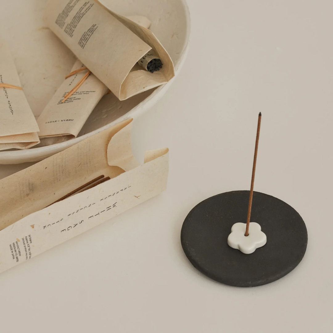 Black Clay Incense Plate - Handcrafted smudging bowl or plate pictured with smoking incense stick resting on on top, and additional sticks in packets in the background - Stocked at LOVINLIFE Co Byron Bay for all your gifts, candles and interior decorating needs