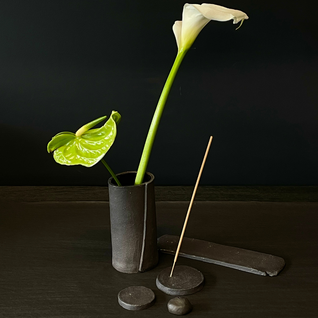 Lovinlife Co ByronBay - Handmade Signature Ceramics Range - Dark Matter Slab Series, matt black stone finish clay pieces - Incense Holders, vases and dishes pictured with the vase holding a white lilys and the round flat incense holder holding a smoking incense stick - available at LOVINLIFE Co Byron Bay for all your gifts, candles and interior decorating needs
