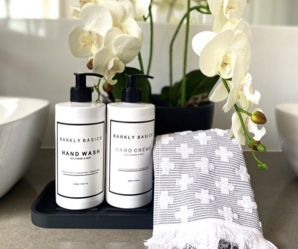 Barkly Basics - Hand wash and Hand Cream bottles with grey and white hand towel on bathroom bench infront of orchids - Stocked at LOVINLIFE Co Byron Bay for all your gifts, candles and interior decorating needs