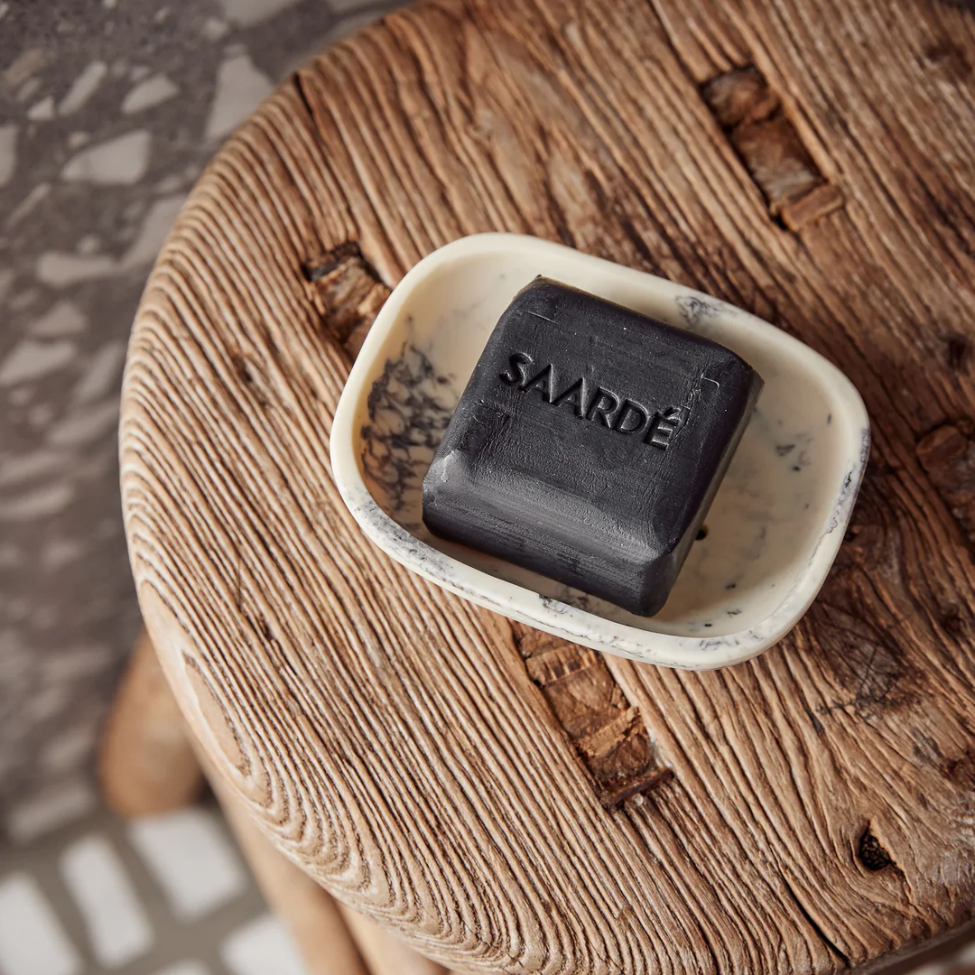 Lovinlife Co ByronBay – Saarde Charcoal Olive Oil Bar Soap – Activated Charcoal for deep cleaning, gentle exfoliation, absorbing excess oil - unscented – soap bar pictured from above in cream resin soap dish on wooden stool - available at LOVINLIFE Co Byron Bay for all your gifts, candles and interior decorating needs