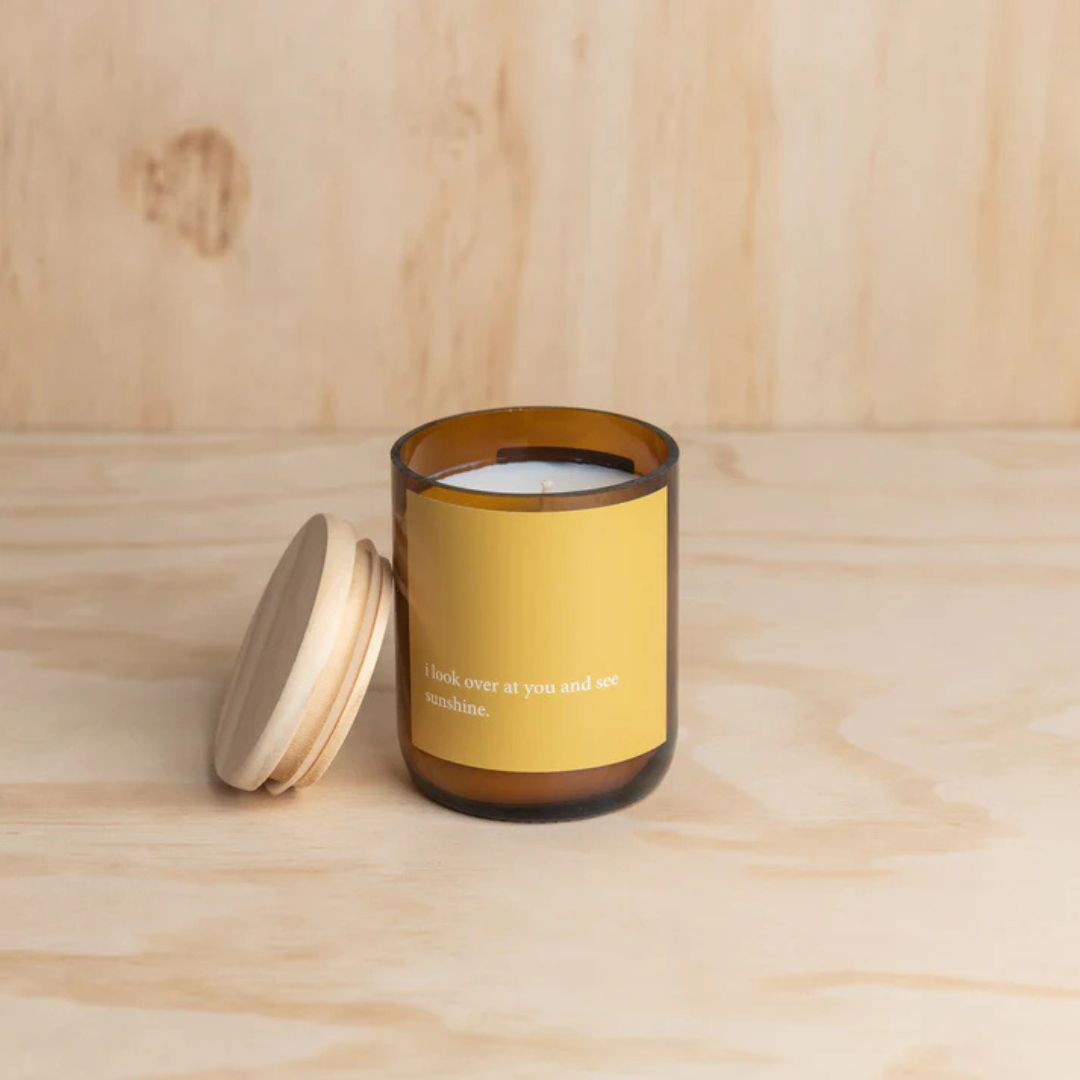 Commonfolk Heartfelt Candle - Wanaka scent with geranium + lavender - "I look over at you and see Sunshine" jar pictured on plywood backdrop, with candle jar lid resting on the side of the open jar - Stocked at LOVINLIFE Co Byron Bay for all your gifts, candles and interior decorating needs