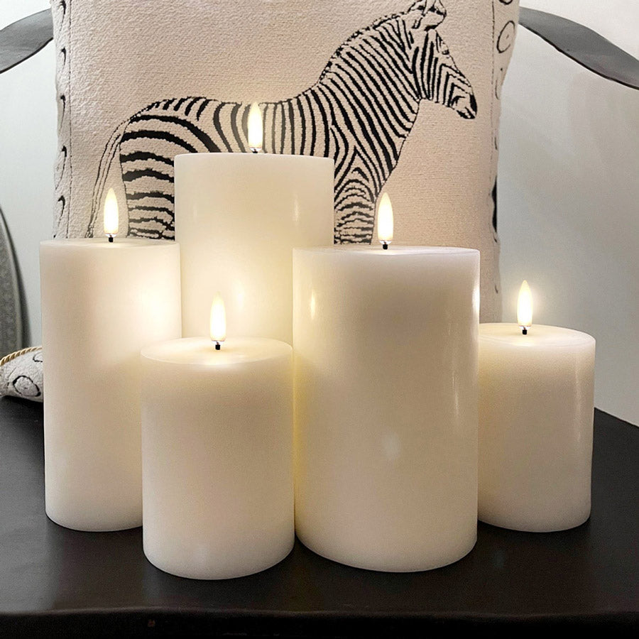 Battery Operated LED Wax Candles - UYUNI 7.8cm Diameter. Made from Nordic White wax to look and feel real, these hand-crafted battery operated luxury flameless candles are all remote enabled, with timer and dimmer options, allowing you to personalise every occasion. A group of candles pictured together in front of a cushion with a zebra print - Stocked at LOVINLIFE Co Byron Bay for all your gifts, candles, homewares and interior decorating needs