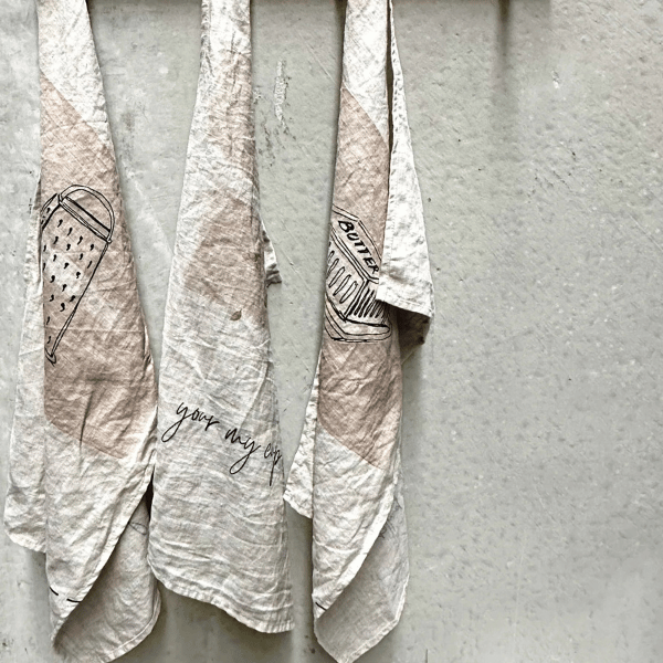 3 x French Linen Tea Towels pictured hanging on hooks. Designed in Australia, Heaven In Earth, available at LOVINLIFE Co Byron Bay