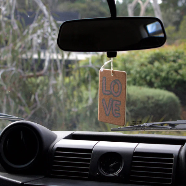 LOVE design Air Freshener tags - Made from 100% post-consumer materials - BIARRITZ SCENT: jasmine, saffron + musk, Feel allured as you indulge in this poetic union that is luxe and luminous, yet grounding - Pictured hanging from rear vision mirror. Stocked at LOVINLIFE Co Byron Bay for all your gifts, candles and interior decorating needs