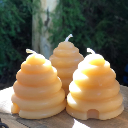 Three pure beeswax beehive-shaped candles on a wooden surface with a blurred natural background. Stocked at LOVINLIFE Co Byron Bay for all your gifts, candles and interior decorating needs