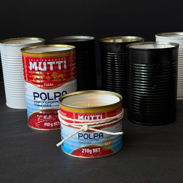 Collection of recycled Mutti Polpa tins that've been turned into candles on a dark surface. Designed for outdoors (although can be indoors too) these Hand made candles are fragranced with Citronella and Lemongrass with a touch of Lavender. Recycled tins are filled with soy/plant based wax blended with pure essential oils, intended as a mild deterrent for annoying bugs. Available at LOVINLIFE Co Byron Bay.