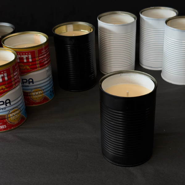 Recycled Mutti Polpa tins that've been turned into candles, pictured on a dark surface. Designed for outdoors (although can be indoors too) these Hand made candles are fragranced with Citronella and Lemongrass with a touch of Lavender. Recycled tins are filled with soy/plant based wax blended with pure essential oils, intended as a mild deterrent for annoying bugs. Available at LOVINLIFE Co Byron Bay.