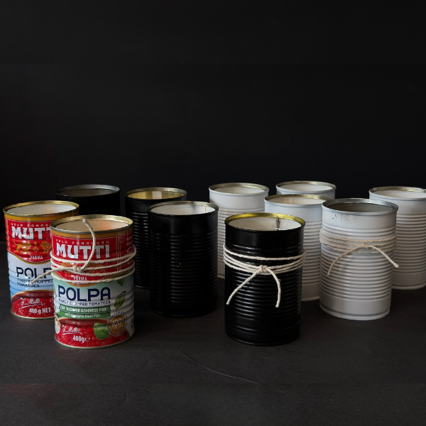 Collection of recycled Mutti Polpa tins that've been turned into candles, pictured on a dark surface. Designed for outdoors (although can be indoors too) these Hand made candles are fragranced with Citronella and Lemongrass with a touch of Lavender. Recycled tins are filled with soy/plant based wax blended with pure essential oils, intended as a mild deterrent for annoying bugs. Available at LOVINLIFE Co Byron Bay.