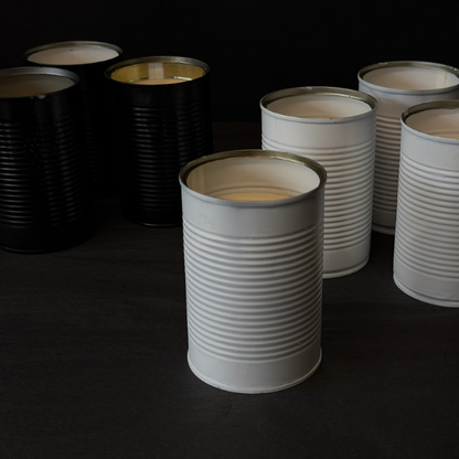 Collection of recycled Black & White tins that've been turned into candles on a dark surface. Designed for outdoors (although can be indoors too) these Hand made candles are fragranced with Citronella and Lemongrass with a touch of Lavender. Recycled tins are filled with soy/plant based wax blended with pure essential oils, intended as a mild deterrent for annoying bugs. Available at LOVINLIFE Co Byron Bay.