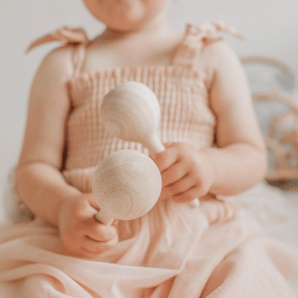 child playing with Maracas made with FSC certified oak wood. All  instruments by Love Note Co are handmade items, non-toxic, eco-friendly and sustainably sourced. Stocked at LOVINLIFE Co Byron Bay for all your gifts, candles and interior decorating needs