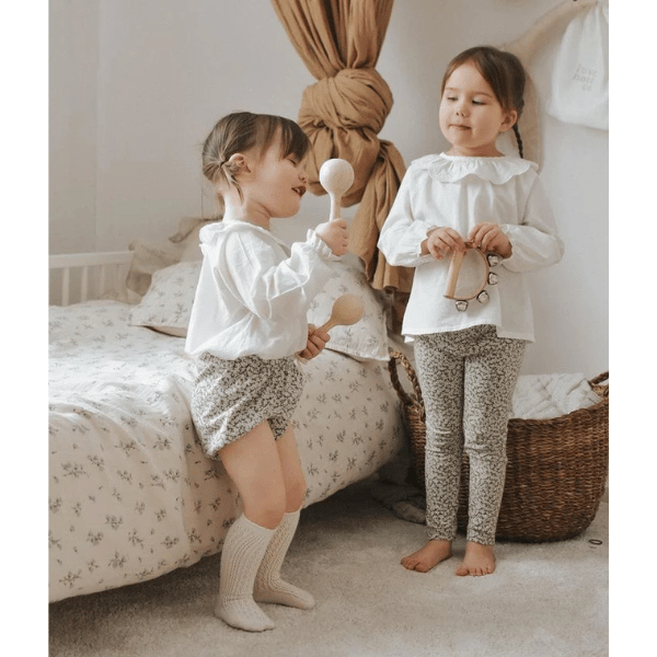 2 x children playing with Little Love Music Set. Set includes: Maracas (x2) Castanets (x2) Tambourine Drum (x1) Hand bells (x1)  Suitcase (x1). Comes with a beautiful in house designed suitcase to pack up and store the instruments in. Made with Wood, iron and leather. All  instruments by Love Note Co are handmade items, non-toxic, eco-friendly and sustainably sourced. Stocked at LOVINLIFE Co Byron Bay for all your gifts, candles and interior decorating needs