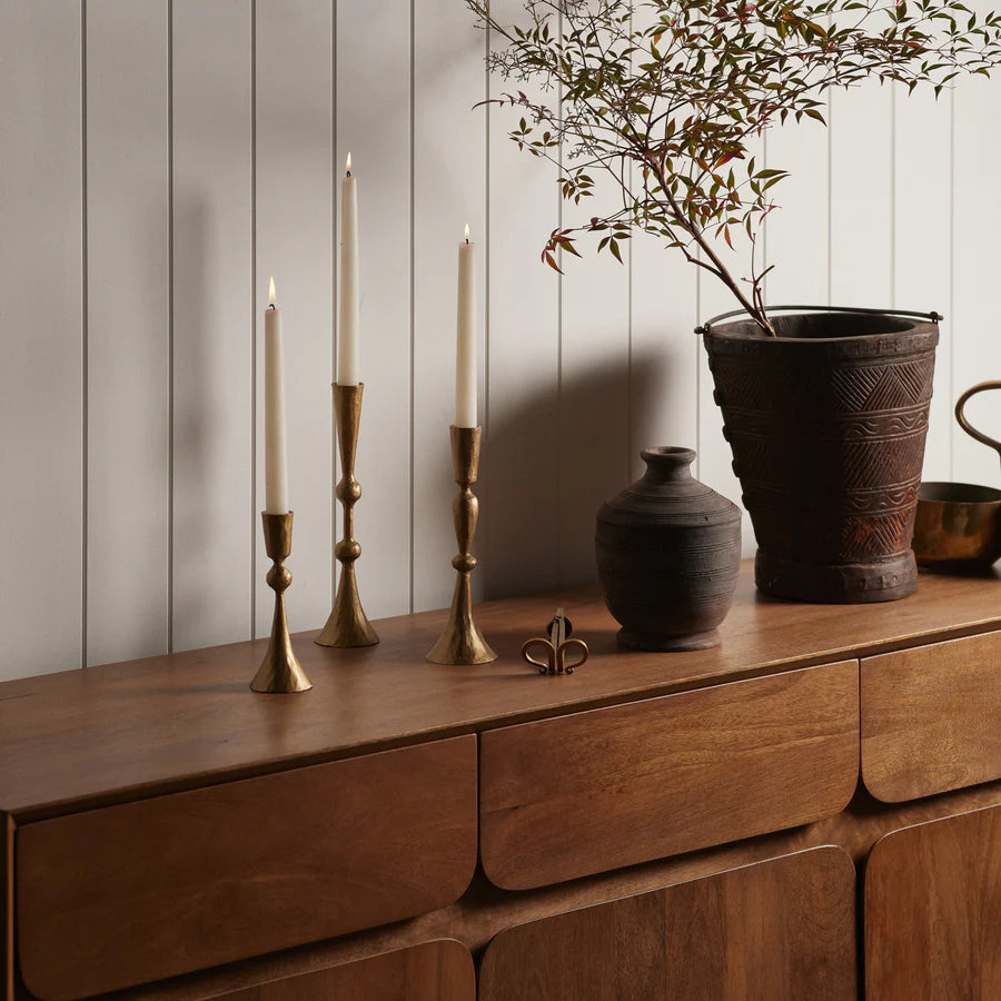 Enchant Brass Candle Stands x 3 all holding white candles on a wooden side board - available at LOVINLIFE Co Byron Bay for all your gifts, candles and interior decorating needs