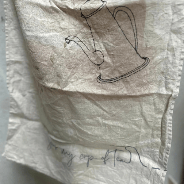 French Linen Tea Towel pictured hanging to show a sketch of a Tea Pot and the words "your my cup of Tea..." printed underneath. Designed in Australia, Heaven In Earth, available at LOVINLIFE Co Byron Bay