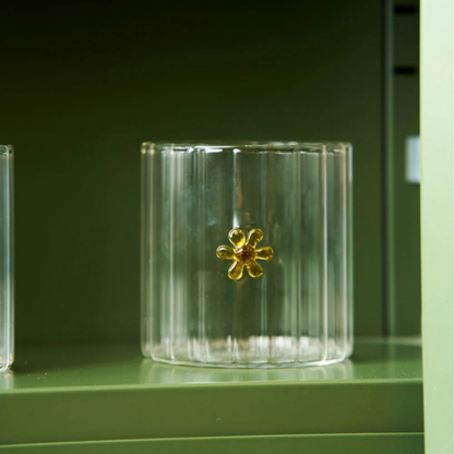 Clear glass tumbler with a yellow flower, pictured on a green shelf. Part of the Robert Gordon Collection stocked at LOVINLIFE Co Byron Bay for all your gifts, candles, homewares and interior decorating needs