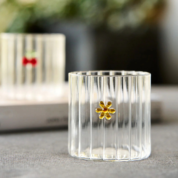 Clear glass tumbler with a yellow flower on a table. Part of the Robert Gordon Collection stocked at LOVINLIFE Co Byron Bay for all your gifts, candles, homewares and interior decorating needs
