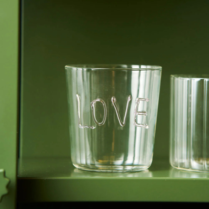 Clear glass tumbler with 'LOVE' engraving on a green shelf. Part of the Robert Gordon Collection stocked at LOVINLIFE Co Byron Bay for all your gifts, candles, homewares and interior decorating needs