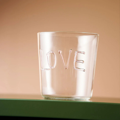 Clear glass tumbler with 'LOVE' engraving on a beige background. Part of the Robert Gordon Collection stocked at LOVINLIFE Co Byron Bay for all your gifts, candles, homewares and interior decorating needs