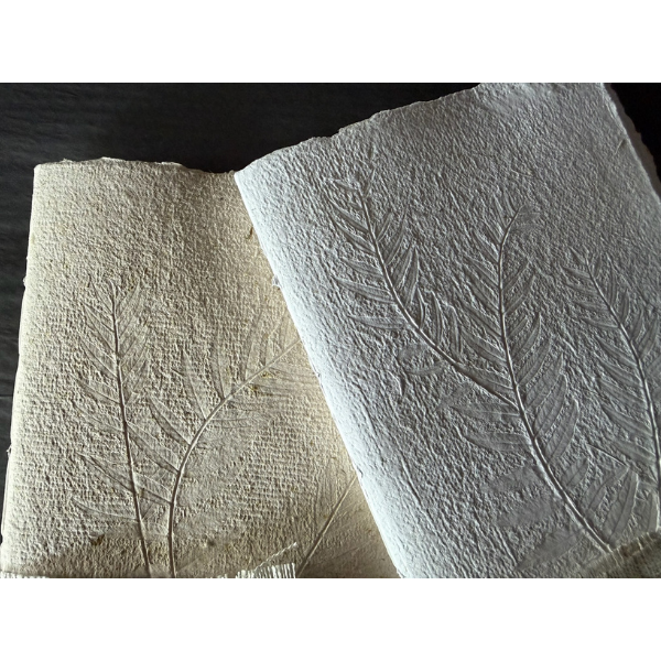 Flat lay close up of the texture of 2 x Hand Pressed Paper A5 Notebooks 20 page in white and natural, with the cover of each embossed with natural grasses. Stocked at LOVINLIFE Co Byron Bay for all your gifts, candles and interior decorating needs 