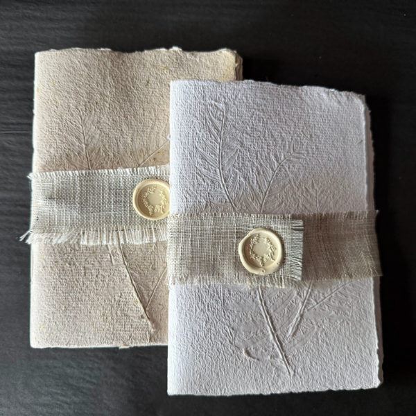 Flat lay of 2 x Hand Pressed Paper A5 Notebooks 20 page in white and natural, with the cover of each embossed with natural grasses. Stocked at LOVINLIFE Co Byron Bay for all your gifts, candles and interior decorating needs 