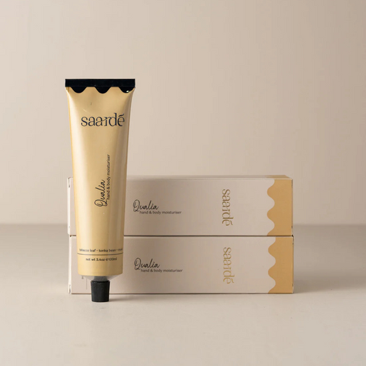Hand & Body Moisturiser by Saarde - Qualia - pictured with tube standing up next to two boxed tubes lying stacked on top of each other - Stocked at LOVINLIFE Co Byron Bay for all your gifts, candles and interior decorating needs