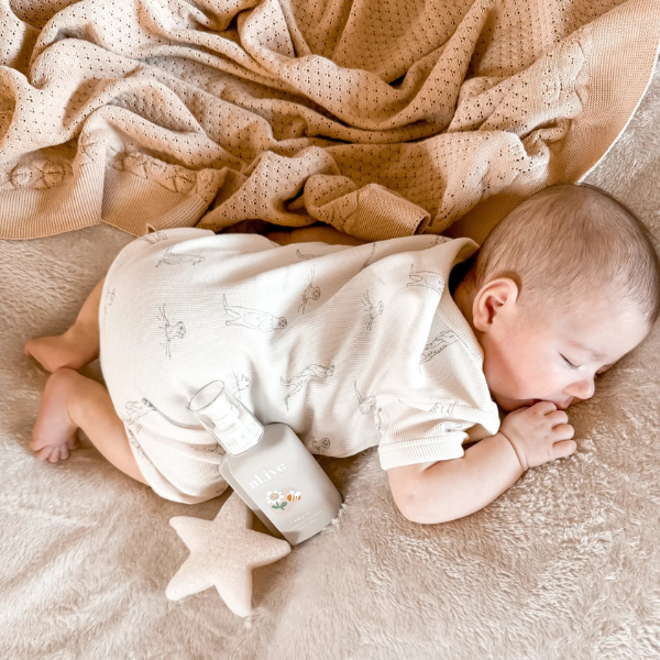 Baby lying on a soft surface with an organic cotton textured Knit Heirloom Baby Blanket in Sand and star-shaped toy. Stocked at LOVINLIFE Co Byron Bay for all your gifts, candles and interior decorating needs