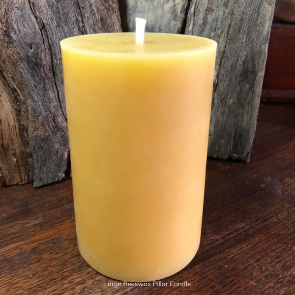 Large pure beeswax pillar candle with pure cotton wick on a wooden surface with a rustic background. Stocked at LOVINLIFE Co Byron Bay for all your gifts, candles and interior decorating needs