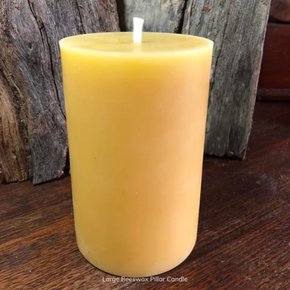 Large pure beeswax pillar candle with pure cotton wick on a wooden surface with a rustic background. Stocked at LOVINLIFE Co Byron Bay for all your gifts, candles and interior decorating needs