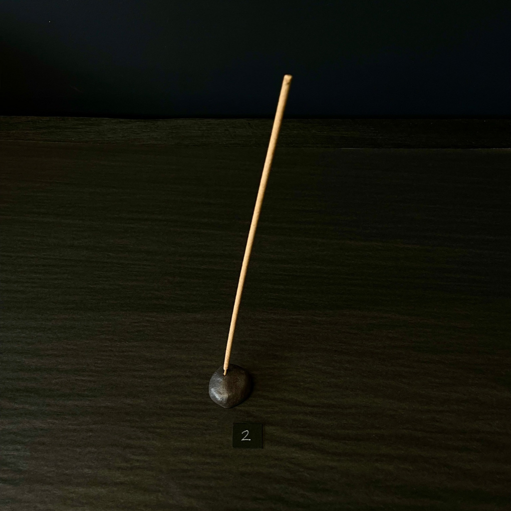 Lovinlife Co ByronBay - Handmade Signature Ceramics Range - Dark Matter Slab Series, matt black stone finish clay pieces - Dark Pebble Incense Holder pictured holding an incense stick - available at LOVINLIFE Co Byron Bay for all your gifts, candles and interior decorating needs