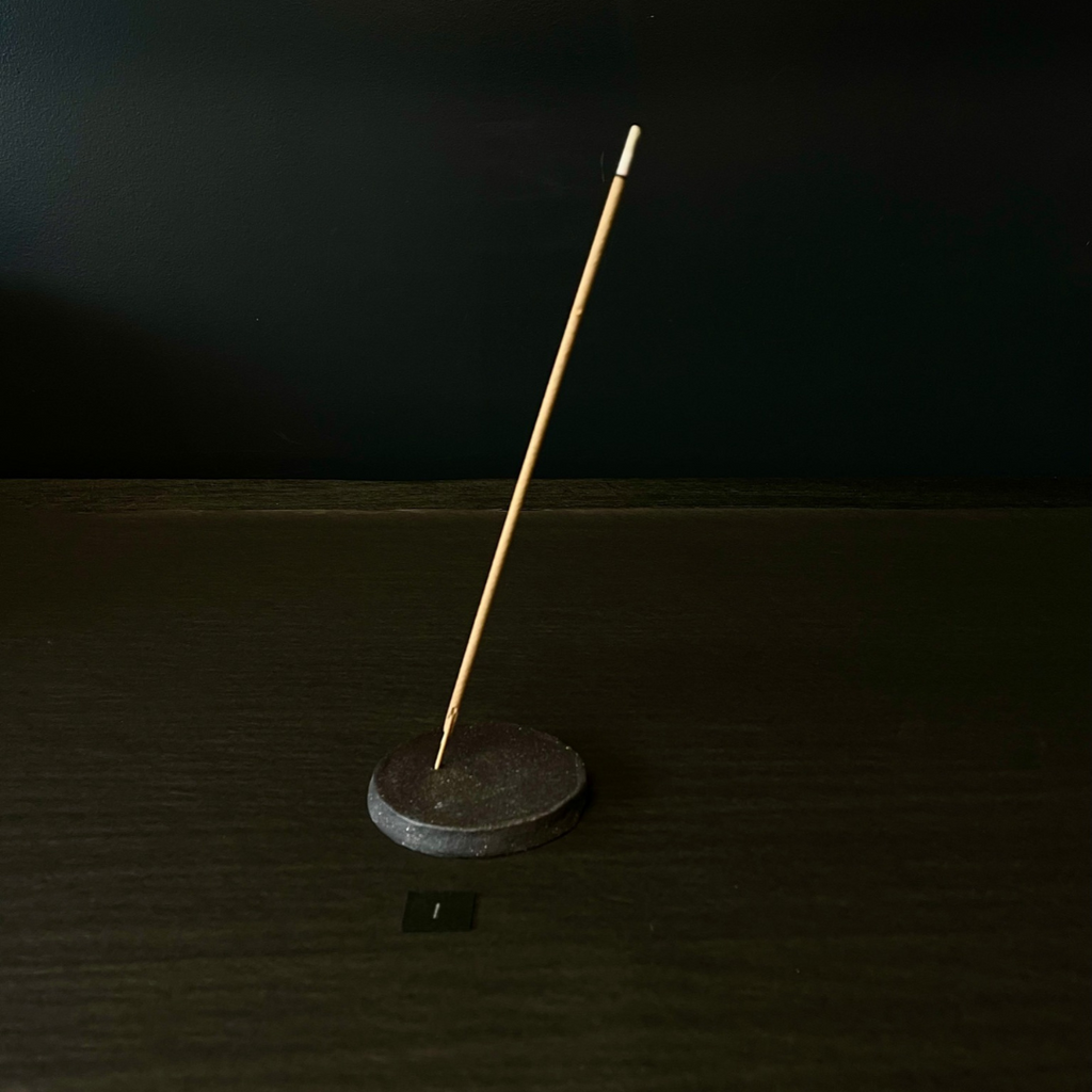 Lovinlife Co ByronBay - Handmade Signature Ceramics Range - Dark Matter Slab Series, matt black stone finish clay pieces - Round Flat Incense Holders pictured holding an incense stick - available at LOVINLIFE Co Byron Bay for all your gifts, candles and interior decorating needs