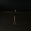 Lovinlife Co ByronBay - Handmade Signature Ceramics Range - Dark Matter Slab Series, matt black stone finish clay pieces - Round Flat Incense Holder number 2 pictured holding a smoking incense stick - available at LOVINLIFE Co Byron Bay for all your gifts, candles and interior decorating needs
