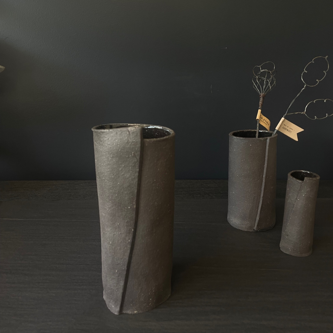 Lovinlife Co ByronBay - Handmade Signature Ceramics Range - Dark Matter Slab Series, matt black stone finish clay pieces - Slab Fold Vase 4 pictured in front with two smaller size vases, one holding twisted wire decorations in background - available at LOVINLIFE Co Byron Bay for all your gifts, candles and interior decorating needs