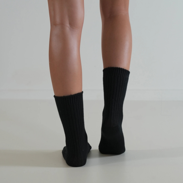 Black socks on a person’s feet, back view, on a plain background. Luxe Cotton Socks by Number Thirty One made with a soft cotton, wool, and spandex blend. Unisex & One size. Stocked at LOVINLIFE Co Byron Bay for all your gifts, candles and interior decorating needs