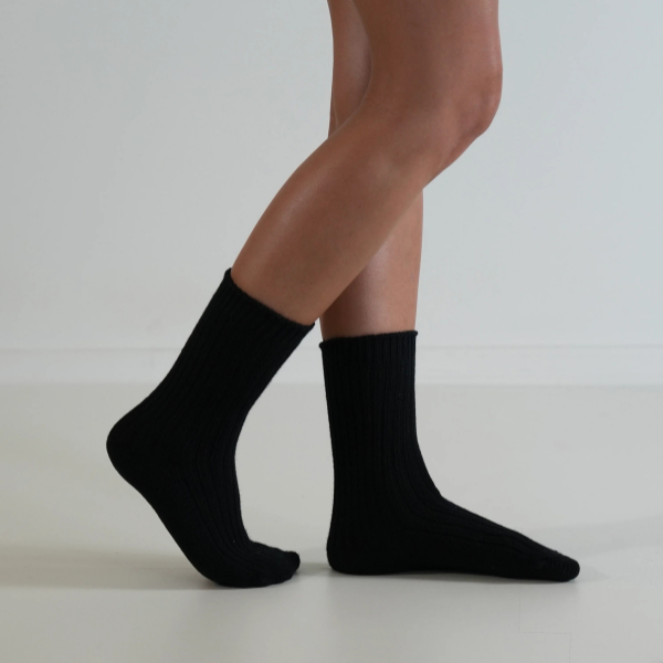 Black socks on a person’s feet, side view, on a plain background. Luxe Cotton Socks by Number Thirty One made with a soft cotton, wool, and spandex blend. Unisex & One size. Stocked at LOVINLIFE Co Byron Bay for all your gifts, candles and interior decorating needs