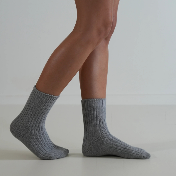 Grey socks on a person’s feet, side view, on a plain background. Luxe Cotton Socks by Number Thirty One made with a soft cotton, wool, and spandex blend. Unisex & One size. Stocked at LOVINLIFE Co Byron Bay for all your gifts, candles and interior decorating needs