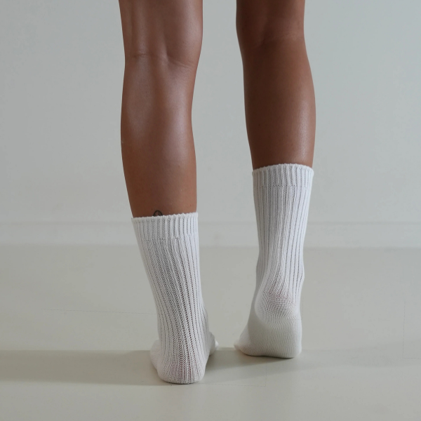 White socks on a person’s feet, back view, on a plain background. Luxe Cotton Socks by Number Thirty One made with a soft cotton, wool, and spandex blend. Unisex & One size. Stocked at LOVINLIFE Co Byron Bay for all your gifts, candles and interior decorating needs