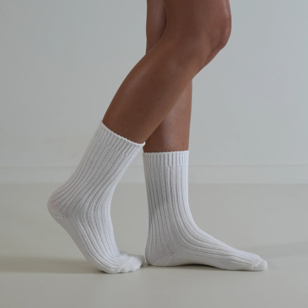 White socks on a person’s feet, side view, on a plain background. Luxe Cotton Socks by Number Thirty One made with a soft cotton, wool, and spandex blend. Unisex & One size. Stocked at LOVINLIFE Co Byron Bay for all your gifts, candles and interior decorating needs