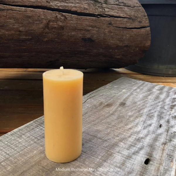 Medium pure beeswax mini pillar candle on a wooden surface, with a pure cotton wick. Stocked at LOVINLIFE Co Byron Bay for all your gifts, candles and interior decorating needs