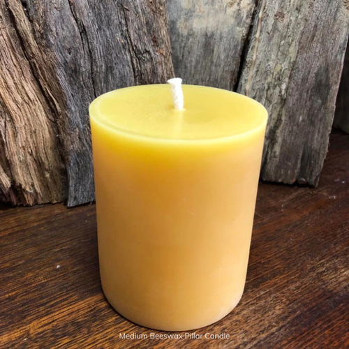 Medium pure beeswax pillar candle with pure cotton wick on a wooden surface with a rustic background. Stocked at LOVINLIFE Co Byron Bay for all your gifts, candles and interior decorating needs