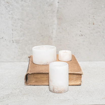 Alabaster Votive Candles by Natures Atelier - large and small sizes pictured standing on top of an old book, with the medium size candle standing in front - Stocked at LOVINLIFE Co Byron Bay for all your gifts, candles and interior decorating needs