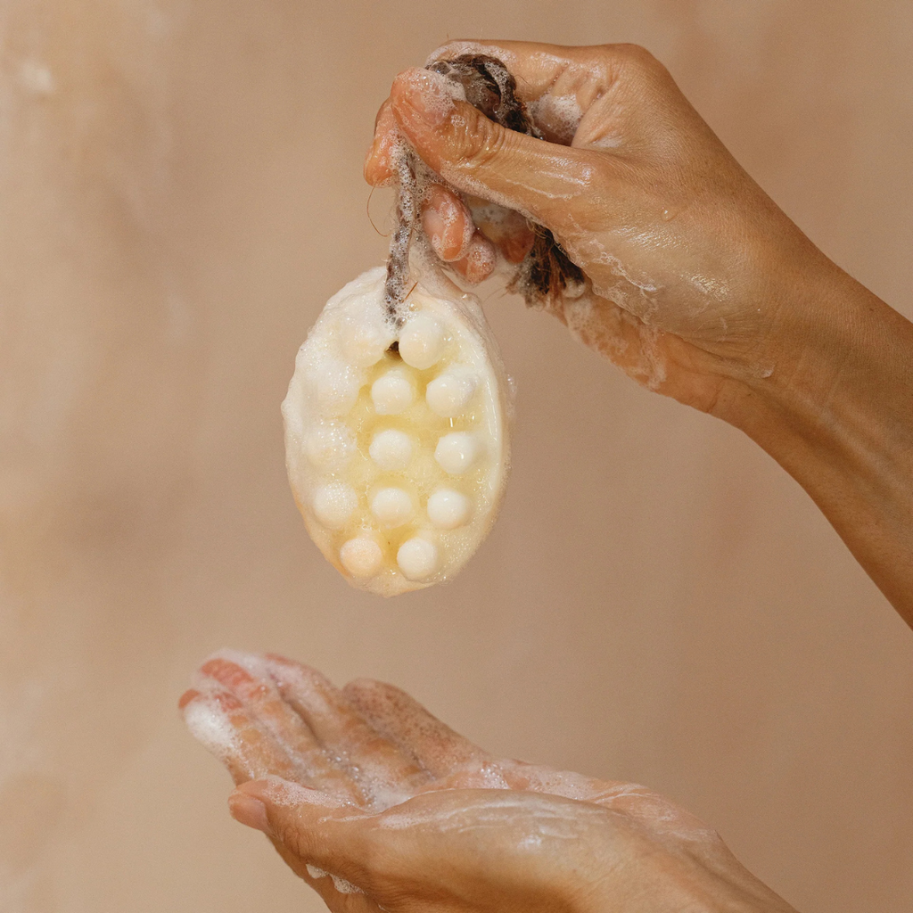 Palo Santo Bar Soap - white - picture of the soap on a rope being held up by the rope above another hand catching the suds - Stocked at LOVINLIFE Co Byron Bay for all your gifts, candles and interior decorating needs