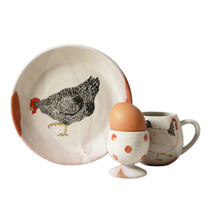 Ceramic plate, egg cup, and mug with chicken design on a white background. A Henny Penny Chickens design, part of the Robert Gordon Collection stocked at LOVINLIFE Co Byron Bay for all your gifts, candles, homewares and interior decorating needs