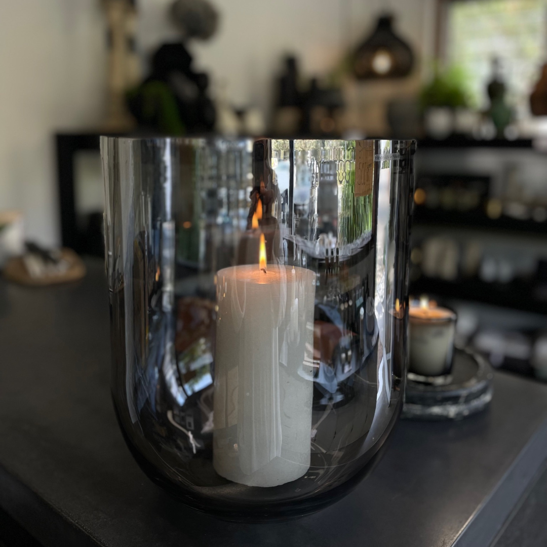 Round Base Candle Holder / Vase from Francalia in Lustre Black, pictured in foreground holding large white pillar candle, with the shop in the background - Stocked at LOVINLIFE Co Byron Bay for all your gifts, candles and interior decorating needs