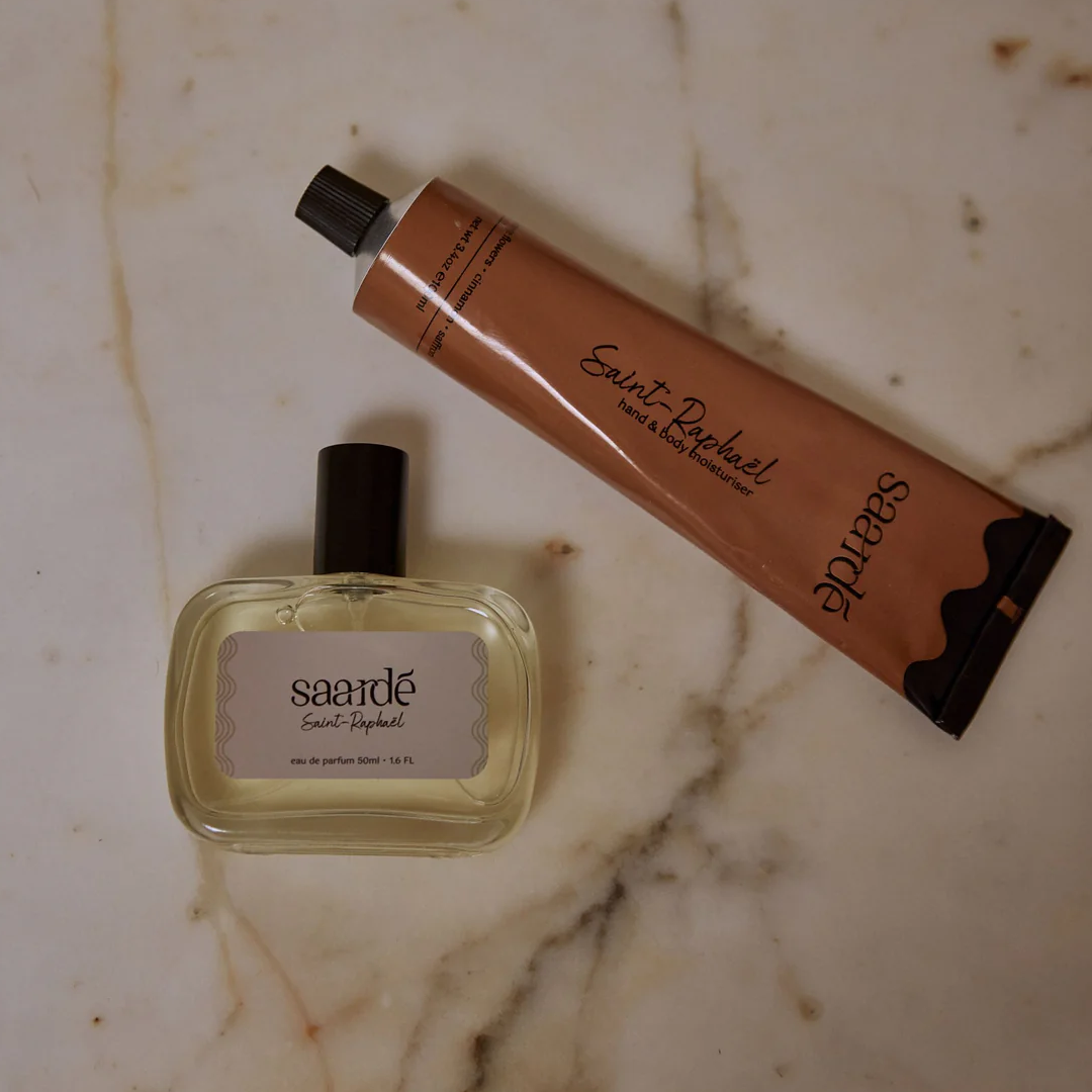 Lovinlife Co ByronBay – Saarde Saint-Raphaël hand and body moisturiser - orange blossom, saffron, lemon and cinnamon scents – pictured as flat lay with perfume and moisturiser tube on a marble bench - available at LOVINLIFE Co Byron Bay for all your gifts, candles and interior decorating needs