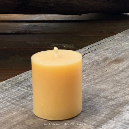 Small pure beeswax mini pillar candle on a wooden surface, with a pure cotton wick. Stocked at LOVINLIFE Co Byron Bay for all your gifts, candles and interior decorating needs