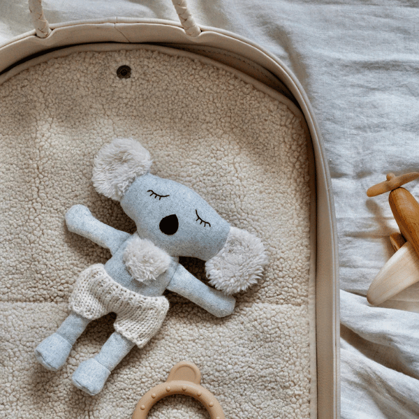 Soft Toy Koala called Bernard, lying in a crib, made from beautifully soft wool-blend fabric with the cosiest cream knitted pants in Australian merino wool - Available at LOVINLIFE Co Byron Bay