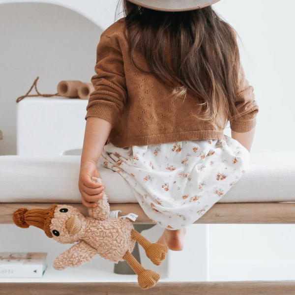 Girl in floral dress sitting on a bench holding her Soft Toy Duck made from a unique cotton plush fabric with caramel corduroy accents and Australian merino wool knitted beanie - Duck Petunia - Available at LOVINLIFE Co Byron Bay