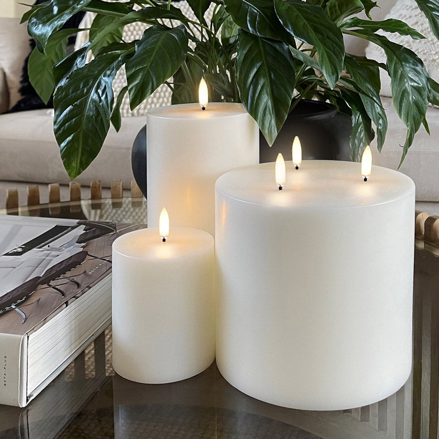 Battery Operated LED Wax Candles - UYUNI Triple Wick. Made from Nordic White wax to look and feel real, these hand-crafted battery operated luxury flameless candles are all remote enabled, with timer and dimmer options, allowing you to personalise every occasion. Three candles pictured together on a coffee table with a plant behind. Stocked at LOVINLIFE Co Byron Bay for all your gifts, candles, homewares and interior decorating needs